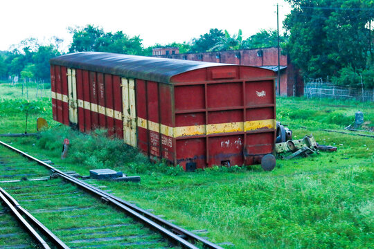 Old Abandoned Red Railway Cargo Boxcar on Tracks in Rural Station