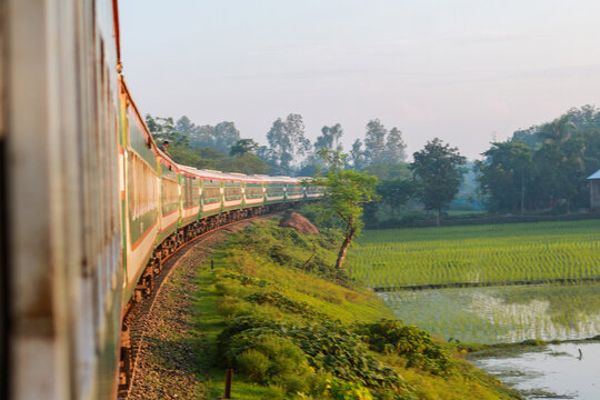 Long Passenger Train Curving Along Rural Green Paddy Fields