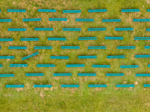 Aerial view of rows of green benches arranged in a grid pattern on a grassy field in Anyksciai, Utena County, Lithuania.