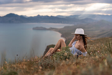 Fototapeta premium Caucasian woman relaxing on mountain top overlooking Crimea coastline during a cloudy summer day