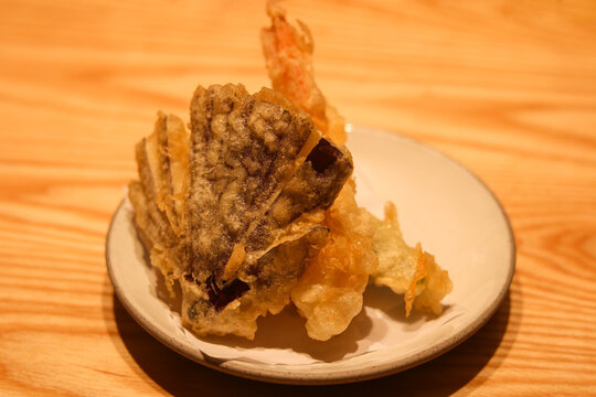 Crispy Japanese tempura platter featuring fan-cut eggplant, ebi prawn, and vegetables fried in a light batter, served on a white ceramic plate.