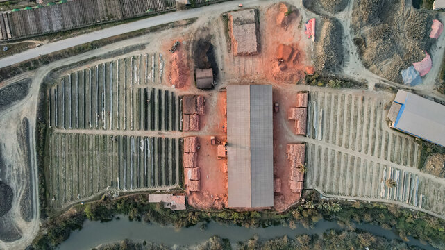 Aerial view of a brick kiln with rows of drying bricks, piles of clay, and a large central structure in Chittagong, Chattogram, Bangladesh.