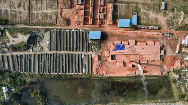 Aerial view of a brickfield featuring rows of drying bricks, a smoking chimney, and industrial structures set within a rural landscape in Chattogram, Chittagong Division, Bangladesh.