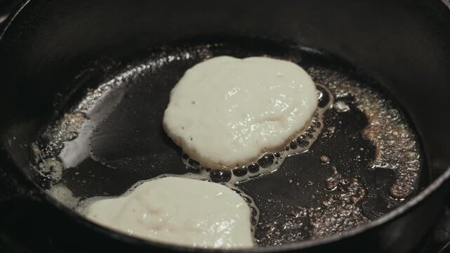 Pancake batter cooks in hot cast iron skillet