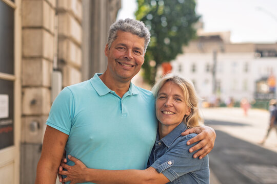 Happy mature couple looking at camera on a city street
