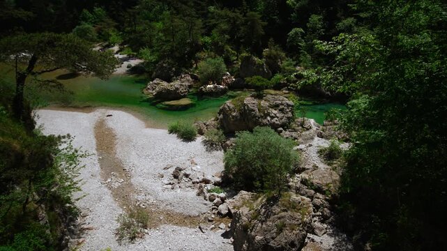 Vibrant emerald mountain river winding through a narrow rocky ravine and dense forest at Pozze Smeraldine.