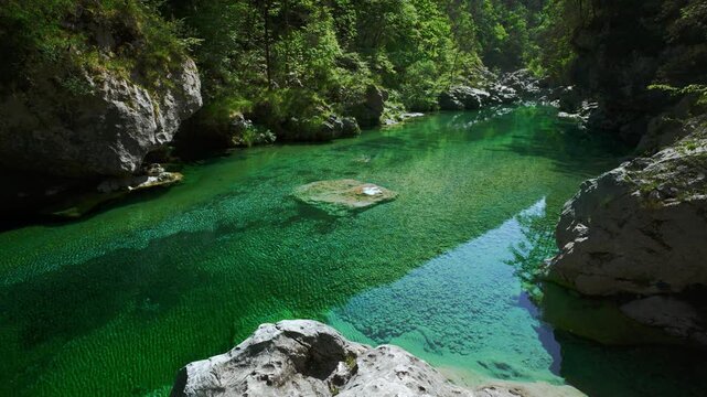 Pristine turquoise water stream flowing gently over smooth white river boulders at Pozze Smeraldine.