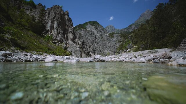 Clear alpine river flowing towards the camera in Friulian Dolomites mountains, Italy. Water level shot