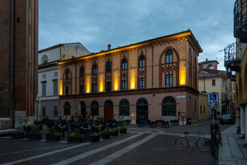 Fototapeta premium Cremona Lombardy historic building facade illuminated at twilight in Piazza del Comune with outdoor cafe
