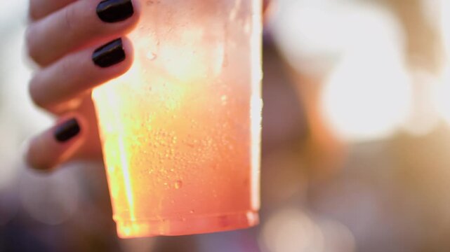 The joyful young woman laughs outdoors with a cocktail in her hands. party at sunset. summer celebration. summer festival. girl with a cocktail outside