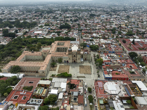 Aerial view of Templo de Santo Domingo de Guzman surrounded by historic colonial architecture, stone plazas, and dense urban rooftops in Oaxaca de Juarez, Oaxaca, Mexico.