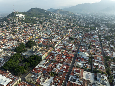 Aerial view of the historic city of Oaxaca de Juarez with its colonial architecture, red-tiled rooftops, and the cathedral, surrounded by mountains in Oaxaca de Juarez, Oaxaca, Mexico.