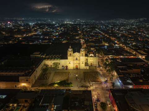 Aerial view of the illuminated Church of Santo Domingo de Guzman at night with lightning in the sky over the city of Oaxaca de Juarez, Oaxaca, Mexico.