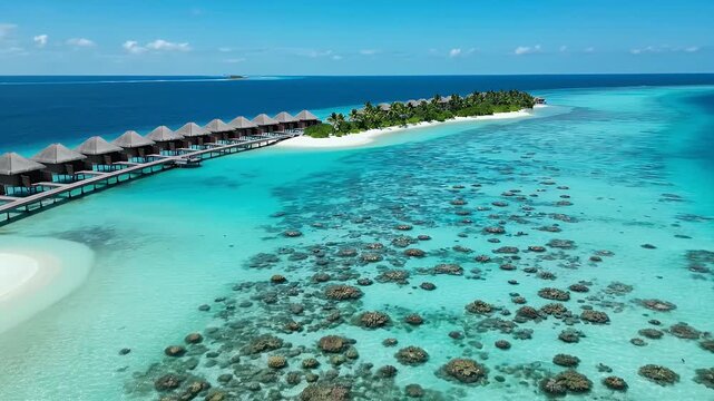 Aerial drone view of a luxury overwater bungalow resort in the Maldives with clear turquoise water and coral reefs