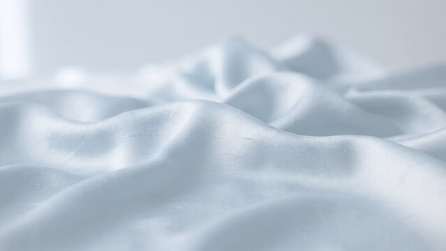 Soft light blue, white satin fabric folds, luxurious smooth textile texture background