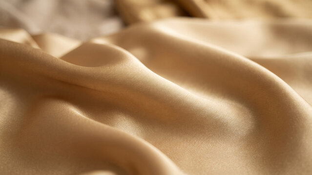 Soft light gold silk satin fabric folds, luxurious smooth textile texture background