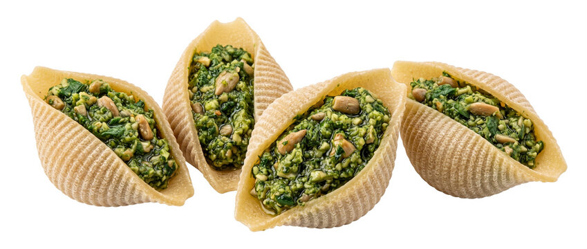 Stuffed conchiglie pasta with spinach pesto and pine nuts isolated on black background, gourmet Italian cuisine appetizer, delicious homemade stuffed shells, fresh basil pasta dish macro shot.