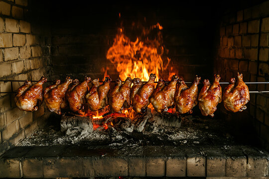 Whole chickens roasting on a spit over an open fire.
