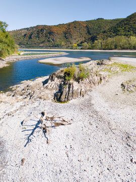 Aerial view of the Rhine riverbed with low water levels, exposed rocks, and driftwood during a drought in the Upper Middle Rhine Valley, Kaub, Rhineland-Palatinate, Germany.