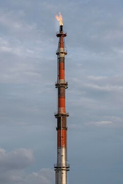 Industrial Gas Flare Stack Burning Against Cloudy Sky at Oil and Gas Facility