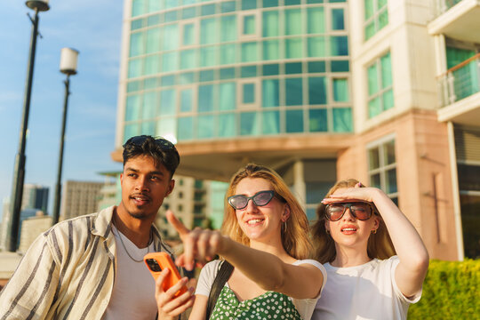 Group of friends exploring a modern city, smiling and pointing during vacation