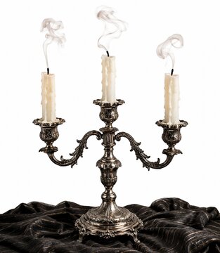 Three smoking white candles in an antique silver candelabra