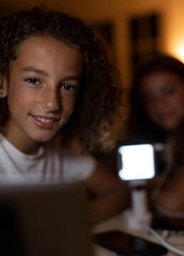 Close-up portrait of a young girl with curly hair. she is smiling and looking directly at the camera. the girl is wearing a white t-shirt and appears to be in her late teens or early thirties.