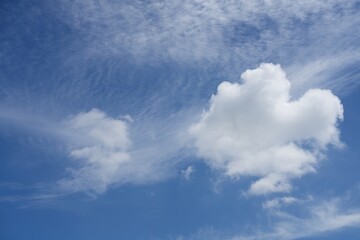 Fototapeta premium Blue sky with soft white clouds and wispy cirrus clouds on a clear sunny day.