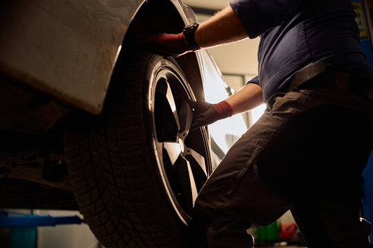 Close up of auto service worker replacing tire on vehicle in repair shop.
