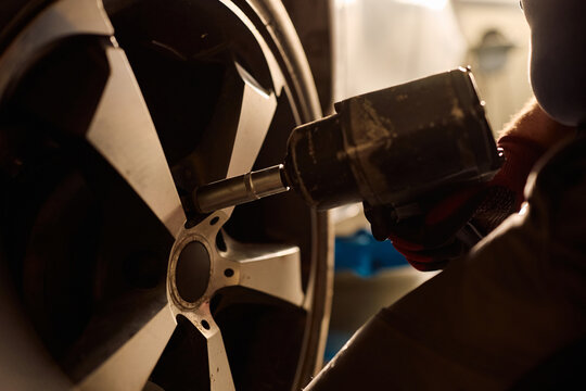 Close up of mechanic tightening wheel bolts at car service.