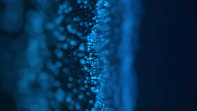 Abstract flowing blue light particles moving in a vertical stream on a dark background vertical-motion glowing-dots data-flow particle-effects motion-background