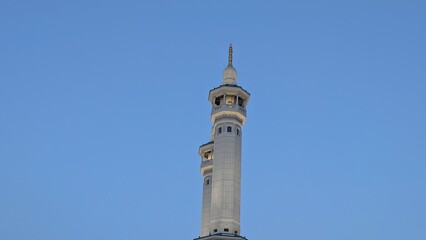 Obraz premium Tall modern minaret against a clear blue sky.