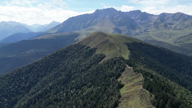 Stunning aerial view of the Plo del Naou mountain ridge and a winding trail through lush forest in the Pyrenees mountains of Occitania, France. Capturing tranquil nature and scenic exploration.