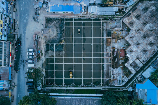 Aerial view of construction site with grid foundation and heavy machinery in urban area in Chattogram, Chittagong Division, Bangladesh.