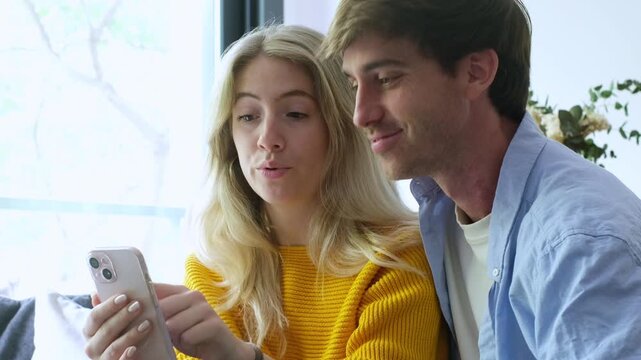 A happy young couple smiling and watching something together, showing affection and enjoying a moment of togetherness, perhaps at home or during leisure time.