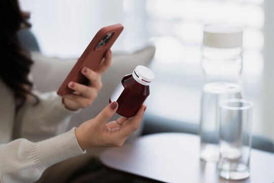 Asian woman checking on medicine bottle at home