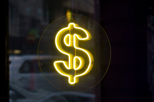 Glowing yellow neon dollar symbol sign.