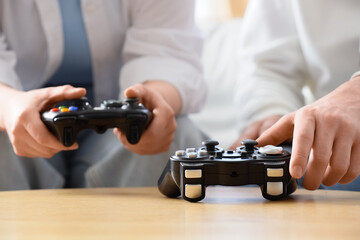 Two people playing video games with black controllers, entertainment and leisure activity, close up on hands and gamepads © Pixel-Shot