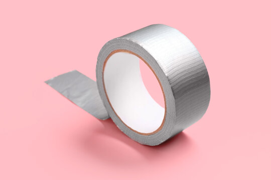 Roll of silver duct tape with a piece unrolled, repair and construction concept, isolated on a pink background