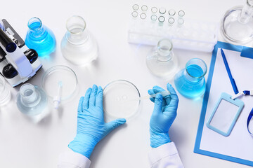 Fototapeta premium Female scientist dropping water sample onto Petri dish at table in laboratory, top view