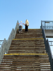 Obraz premium Two people ascend weathered stone steps under clear blue sky
