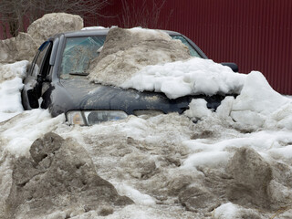 Obraz premium Snow-covered car stuck in deep snow pile. Frozen landscape shows harsh winter weather.