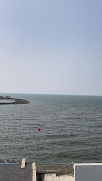 Scenic view of a calm ocean with a clear sky a pier extending into the water and a distant shoreline creating a peaceful and relaxing maritime landscape perfect for travel and leisure themes