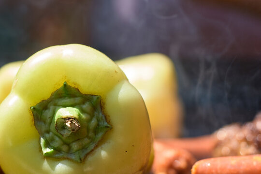 Close-up view of fresh green bell peppers grilling on an open fire barbecue pit