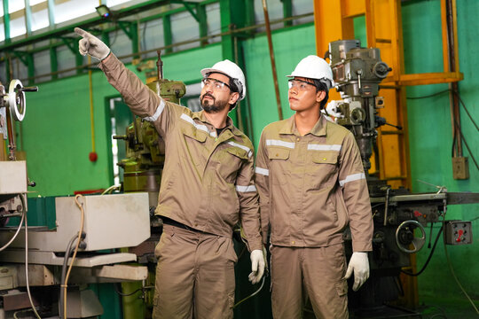 Engineer factory worker hard hat safety helmet machinery industrial pointing inspection teamwork two engineer wearing safety helmet during machinery inspection factory workshop with focused