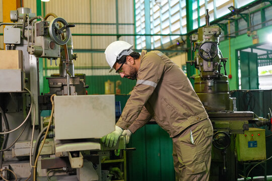 Engineer worker factory machine helmet glove industrial workshop labor safety male technician operating metalworking equipment in manufacturing plant interior
