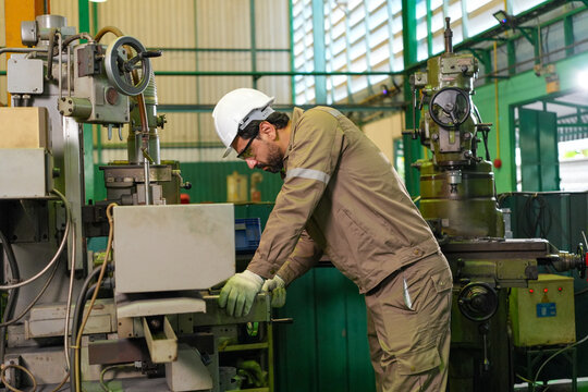 Engineer factory machine worker helmet industry safety maintenance equipment workshop technician inspecting industrial machinery in manufacturing plant with focused expression