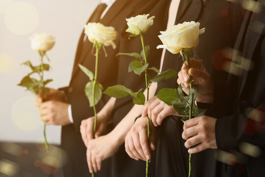 People in black attire holding white roses, funeral and memorial service concept, grief and remembrance