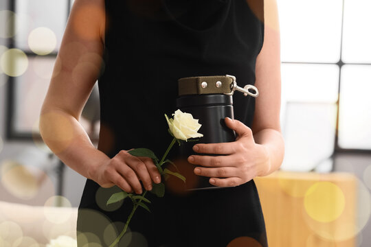 Woman in black dress holding a pet urn with a collar and a white rose, remembrance and loss