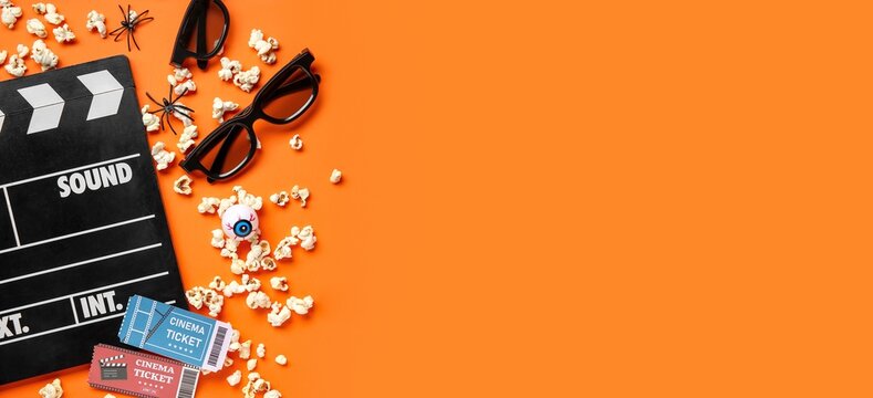 Halloween movie night flat lay with cinema tickets, popcorn, 3d glasses, and spooky decorations on orange background